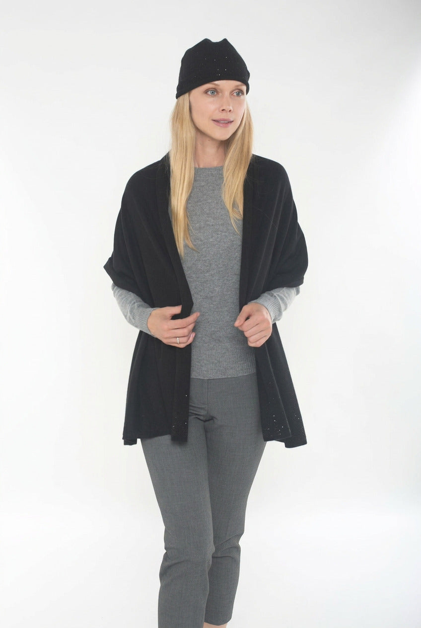 Woman wearing a black cardigan, gray sweater, and pants on a white background